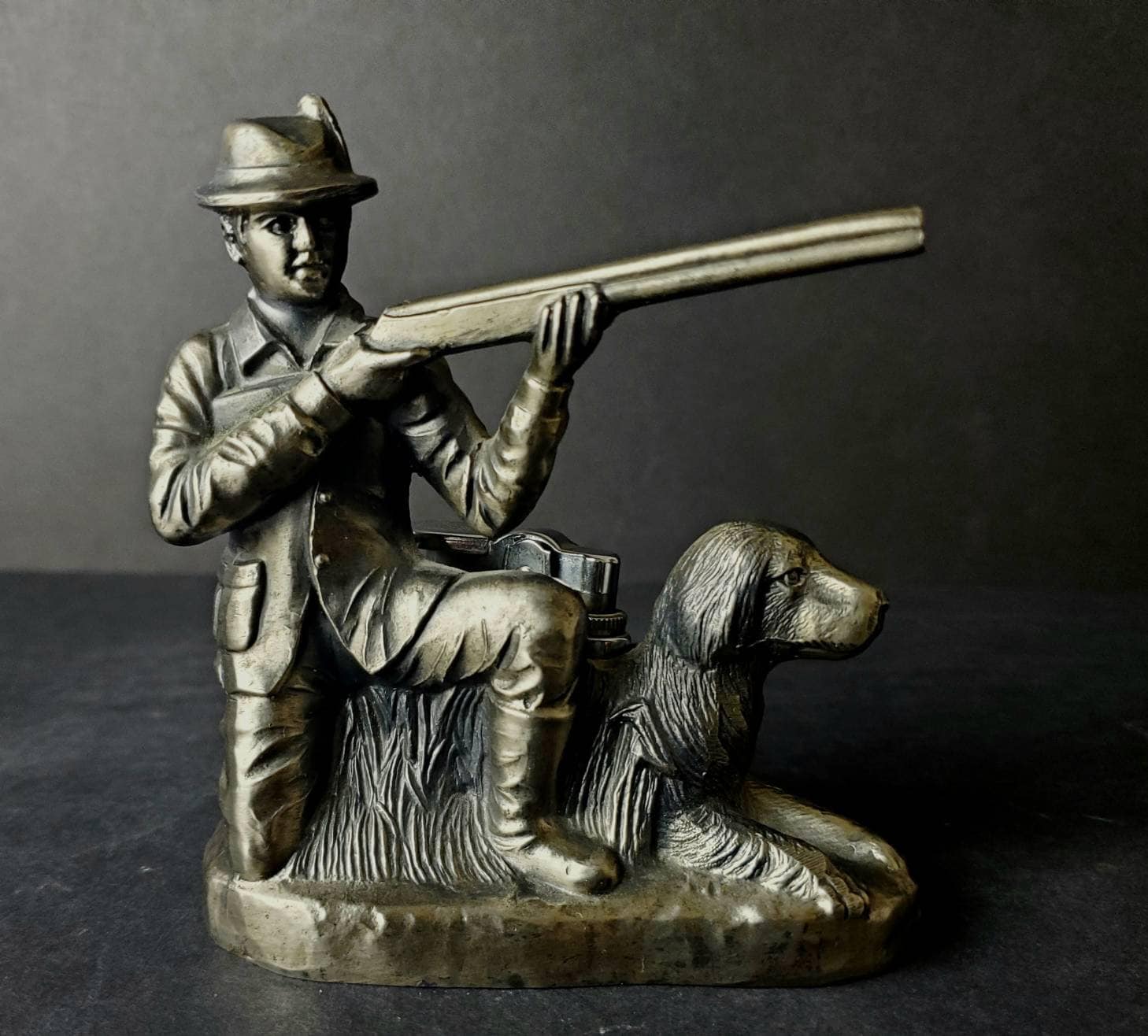 ライフルと犬のテーブルライターを持ったひざまずくハンターの置物
