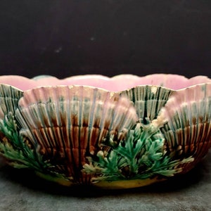 Könnte beinhalten: Eine große, gewellte Keramikschale mit einem rosa, grünen und braunen Blumendesign. Die Schale ist mit einem erhabenen Muster aus Blättern und Blumen verziert.