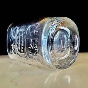 May include: A clear glass cup with a design etched into the side. The design features the words "Disney Studios" and a starburst. The bottom of the cup has the words "Disney World" etched into it.