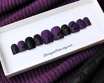 Uñas postizas estilo gótico morado oscuro con estampado de telaraña negra mate para fiestas de Halloween.