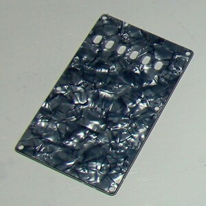 May include: Black and white guitar pickguard with a marbled pattern and five holes.