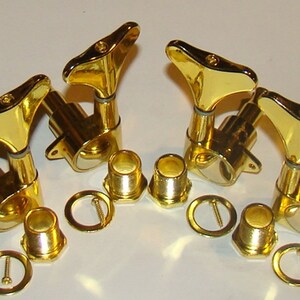 May include: Set of six gold-colored guitar tuning machines, with matching bushings and screws. The tuning pegs have a classic design with a smooth, shiny finish. Ideal for replacing or upgrading guitar hardware.