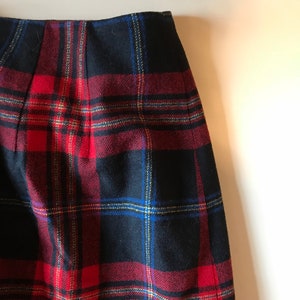 Pode incluir: Uma saia xadrez preta, vermelha e azul. A saia é feita de um tecido grosso e tecido.