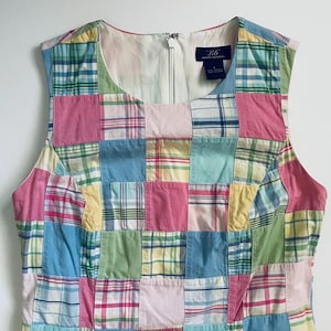May include: A sleeveless dress featuring a patchwork design of various plaid patterns in pastel pink, light blue, yellow, and green. The bodice has a round neckline and a center back zipper. A dark blue label inside reads 3/6 Tommy Hilfiger.