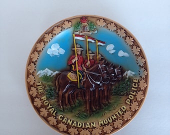 Plato conmemorativo de Canadá con la Real Policía Montada de Canadá, miembros de la Policía Montada a caballo cerca de las montañas, colores brillantes, diseño en relieve y hojas de arce.