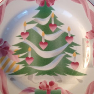 Op de afbeelding: Een wit keramiek bord met een groen kerstboomontwerp. De boom is versierd met roze harten, witte kaarsen en roze linten. Een groene cadeaudoos met een roze strik bevindt zich onderaan het bord.