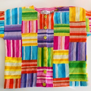 May include: A colorful striped cardigan with a patchwork design. The cardigan has a button closure and is made of a soft, knitted fabric.