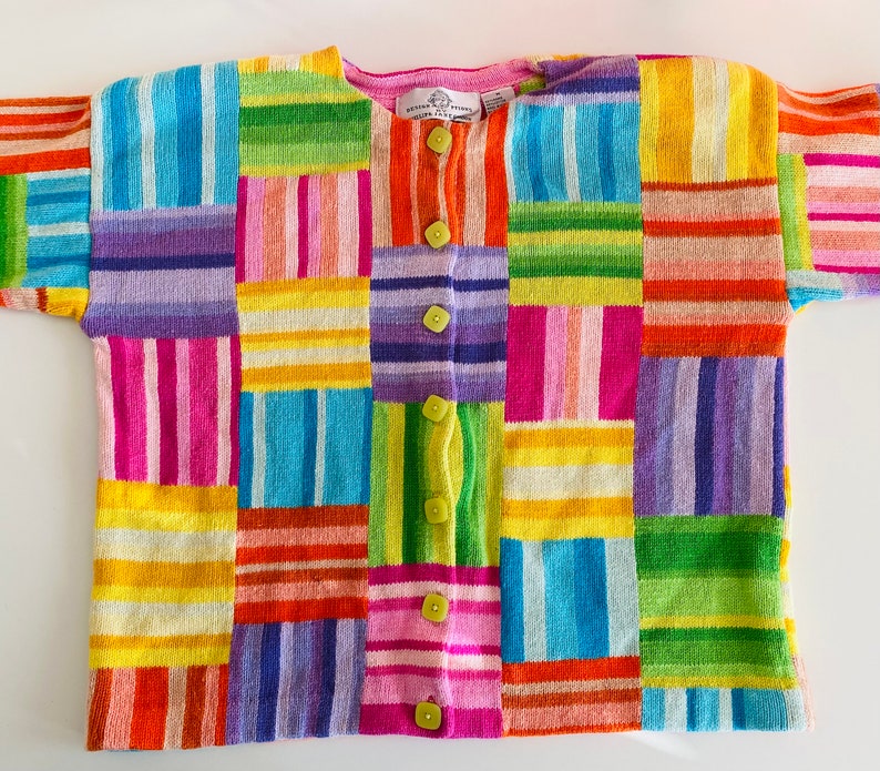 May include: A colorful striped cardigan with a patchwork design. The cardigan has a button closure and is made of a soft, knitted fabric.