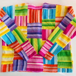 May include: A colorful knitted sweater with a patchwork design featuring stripes of pink, blue, green, yellow, and purple.