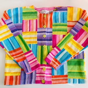 May include: A colorful striped cardigan with a button-up front. The cardigan is made of a soft, knitted fabric and features a variety of bright colors, including pink, blue, green, yellow, and orange.