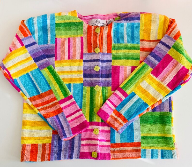 May include: A colorful striped cardigan with a button-up front. The cardigan is made of a soft, knitted fabric and features a variety of bright colors, including pink, blue, green, yellow, and orange.