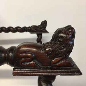 May include: A dark brown wooden chair with a carved lion's head on the front leg. The chair has a twisted design on the legs and a carved lion's head on the armrest.