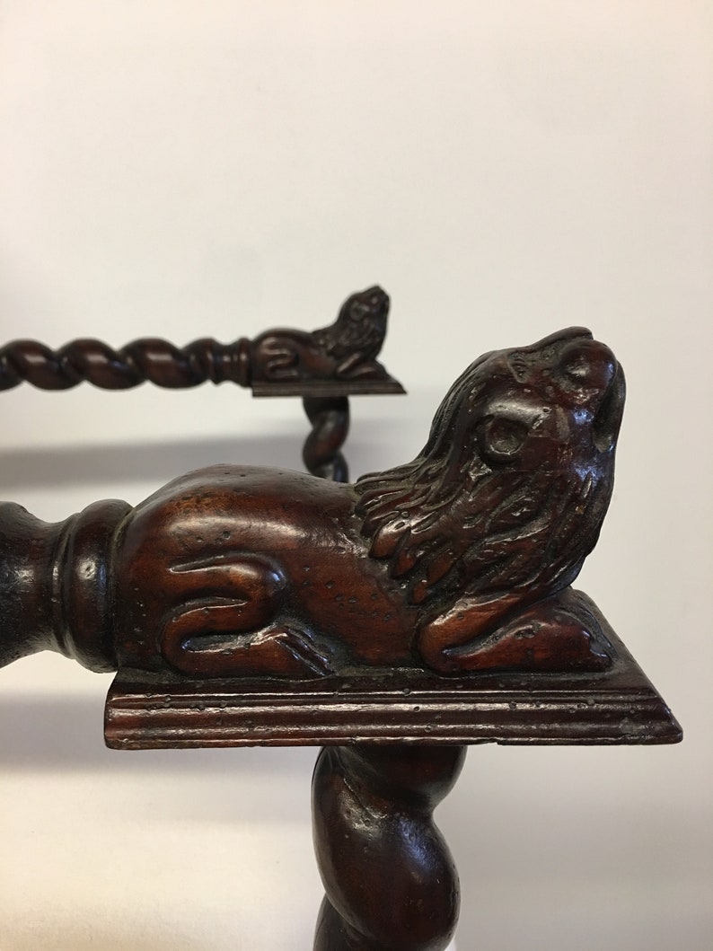 May include: A dark brown wooden chair with a carved lion's head on the front leg. The chair has a twisted design on the legs and a carved lion's head on the armrest.