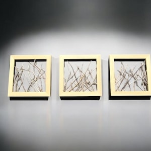 May include: Three framed wall art pieces with a light wood frame and a white background. Each frame features a design of thin, light brown branches.