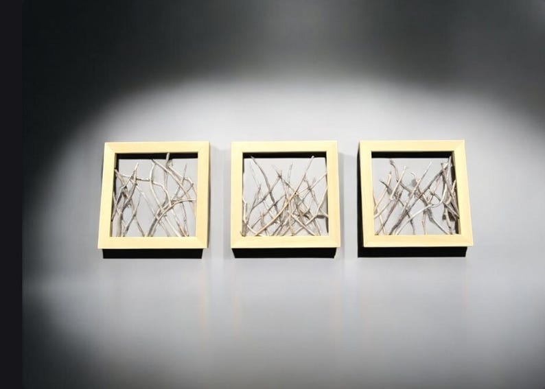 May include: Three framed wall art pieces with a light wood frame and a white background. Each frame features a design of thin, light brown branches.