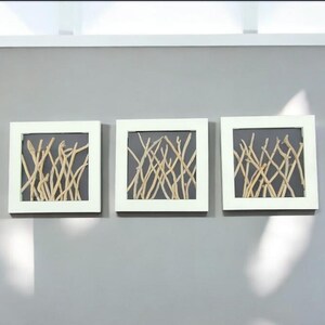 May include: Three white framed square wall art pieces with a gray background and a pattern of light brown twigs.