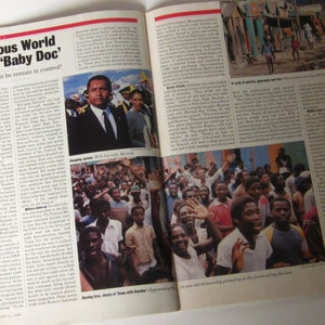 May include: A black and white photo of a man in a suit standing with a group of people. The man is smiling and the people are looking at the camera. The photo is taken in a street setting. The caption reads "The Perilous World of Haiti's 'Baby Doc' How much longer can he remain in control?"