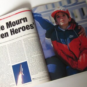 May include: A magazine cover with the headline "We Mourn Seven Heroes." The cover features a young boy wearing a red and blue jacket with the Nike logo. The boy is sitting on the lap of an adult, who is wearing a blue shirt. The magazine cover is about the space shuttle tragedy.