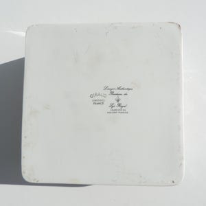 Pu&ograve; includere: Piatto quadrato in ceramica bianca con un logo in bianco e nero che recita "Giraud Limoges France" e "Limoges Authentique Porcelaine de Luxe Lys Royal Coupe d'or du Bon Gout Francais".