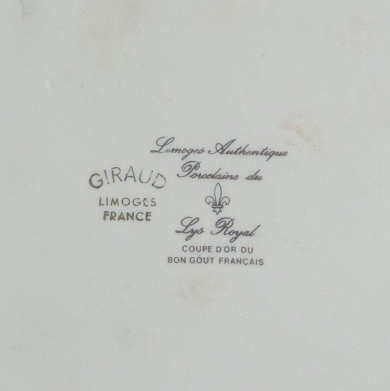 Pu&ograve; includere: Un piatto in porcellana bianca con una scritta dorata che recita "Limoges Authentique Porcelaine du GIRAUD LIMOGES FRANCE Lys Royal COUPE D'OR DU BON GOUT FRAN&Ccedil;AIS".