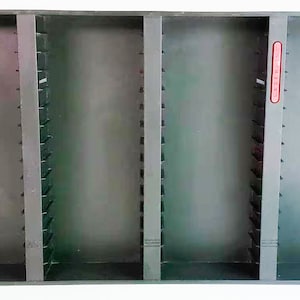 May include: Black plastic wall-mounted storage unit with four compartments for organizing VHS tapes. Each compartment has 12 slots for tapes. The unit has a red label that says "VIDEO CASSETTES".