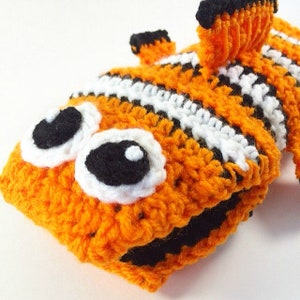 May include: A crocheted orange, white, and black clownfish toy with large black eyes.