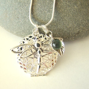 May include: Silver dragonfly charm necklace with a green glass bead and a filigree design.