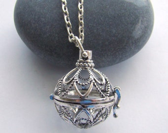 May include: A silver necklace with a delicate, ornate cage pendant. The cage is open and has a small, dangling charm.