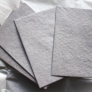 Quatro envelopes de papel cinza feitos à mão com tapete de linho.