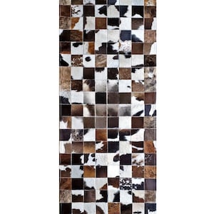 May include: A long rectangular rug made of patchwork cowhide. The rug is made up of squares of different colours and patterns of brown, black, and white cowhide.