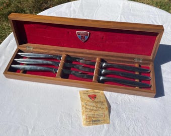 May include: A set of three silver-toned stainless steel knives with integrated handles, housed in a rectangular wooden box with a red velvet interior. The box lid features a Gerber Legendary Blades shield emblem and includes a paper guarantee card.