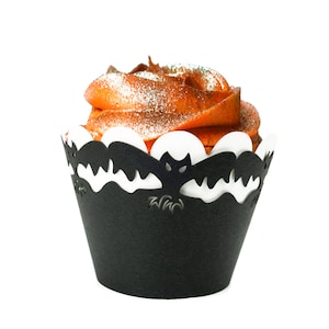 May include: A black cupcake liner with a bat design and a swirl of orange frosting topped with sprinkles.