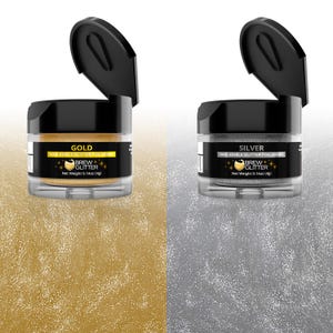May include: Two small jars of edible glitter for drinks. The jars are labeled "Gold" and "Silver" and contain 100% edible glitter. Each jar has a black lid and a clear body, and the glitter is visible inside.