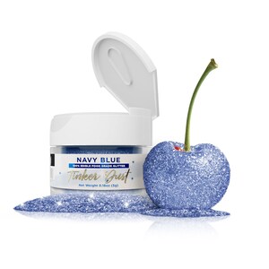 May include: A small jar of navy blue edible glitter labeled "NAVY BLUE 100% EDIBLE FOOD GRADE GLITTER Tinker Just. Net Weight 0.18oz (5g)". The jar is open and a small amount of glitter is spilling out onto a white surface. A blue glitter-covered cherry is next to the jar.