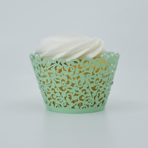 May include: A light green cupcake wrapper with a delicate lace design. The wrapper is empty and ready to hold a cupcake.