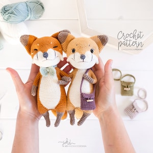May include: Two crocheted fox amigurumi toys, one orange and one brown, holding small crocheted bags. The toys are being held by hands in front of a white background. The text "Crochet pattern" and "Gingerinos & Penny" is visible in the top right corner of the image.