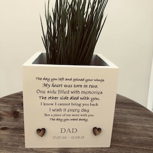 May include: A white wooden planter box with a poem and the word "DAD" printed on the front. Two small wooden hearts are affixed to the front. The planter contains green grass-like plants.