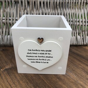 Puede incluir: Una caja de madera blanca con un adorno en forma de corazón. El corazón tiene el texto "Our Auntie is very special...Love Oliver & Leo xx". Un pequeño corazón de madera está encima del texto. La caja está sobre una superficie de madera.