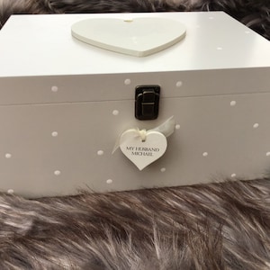 May include: A pale grey wooden box with a white heart-shaped lid and a smaller heart-shaped tag that reads "My Husband Michael". The box has white polka dots and a metal clasp.