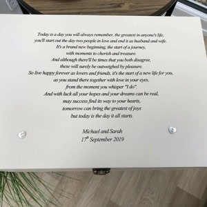 May include: A white wooden keepsake box with a poem and the names "Michael and Sarah" and the date "17th September 2019" printed on the lid. Two heart-shaped embellishments are on the lid. The box is closed with a metal clasp.