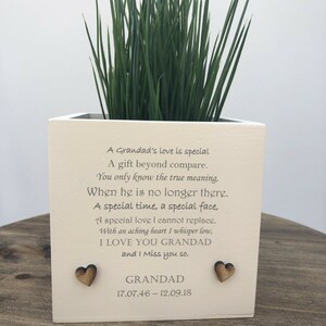 May include: A square, off-white planter with green grass. The planter has a poem and the word "GRANDAD" with dates and two wooden heart accents. The text reads "I LOVE YOU GRANDAD and I Miss you so."