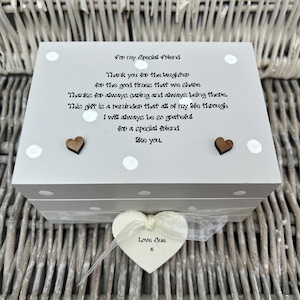 Op de afbeelding: Een grijze houten doos met een wit deksel, versierd met witte stippen en twee kleine houten hartjes. Op het deksel staat de tekst "For my Special Friend" en een oprechte boodschap. Een hartvormig label met "Love Sue" hangt aan de doos.