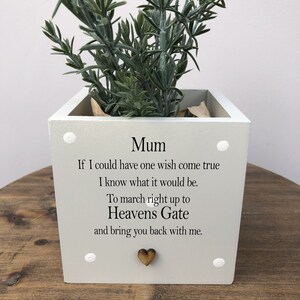 May include: A light grey square planter with the word "Mum" and a touching message in black text. The planter contains a green plant and a small wooden heart. White decorative studs are visible.
