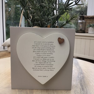 Puede incluir: Una maceta cuadrada gris claro con una placa en forma de corazón y un pequeño corazón de madera. La placa tiene un poema sobre la amistad. La maceta contiene una planta verde. El texto en la placa dice "If I could catch a rainbow...Love Sam x."