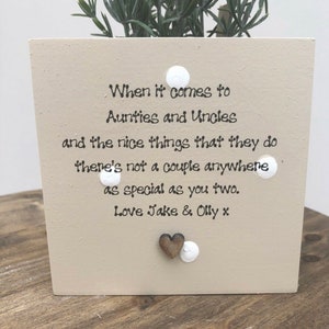 Puede incluir: Una maceta cuadrada beige con una planta, con el texto "When it comes to Aunties and Uncles and the nice things that they do there's not a couple anywhere as special as you two. Love Jake & Olly x". Incluye puntos blancos y un corazón de madera.