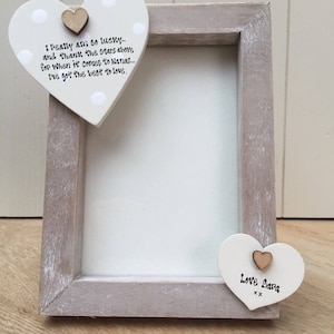 Puede incluir: Un marco de fotos de madera con un acabado gris desgastado. Se adjuntan dos adornos en forma de corazón. Un corazón tiene el texto "I pretty am so lucky...I've got the best to love." El otro corazón dice "Love Sara".