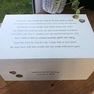 Op de afbeelding: Een witte houten kist met een scharnierend deksel, gegraveerd met een gedicht en de woorden "MEMORIES of my Husband Bill". Decoratieve knopen zijn bevestigd. De kist staat op een houten oppervlak.
