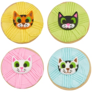 Puede incluir: Cuatro galletas de az&uacute;car decoradas con forma de ovillos de lana con caras de gato en la parte superior. Las galletas son amarillas, verdes, rosas y azules.
