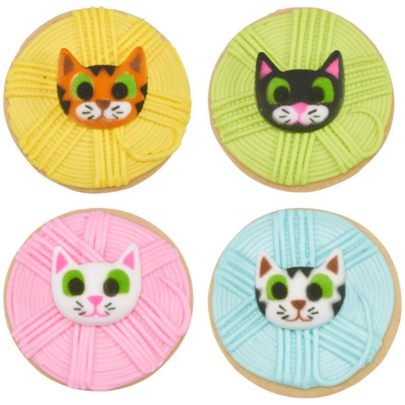 Puede incluir: Cuatro galletas de az&uacute;car decoradas con forma de ovillos de lana con caras de gato en la parte superior. Las galletas son amarillas, verdes, rosas y azules.