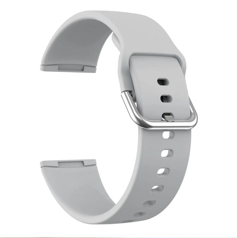 May include: A light gray silicone watch band with a silver buckle. The band has multiple holes for adjusting the fit.